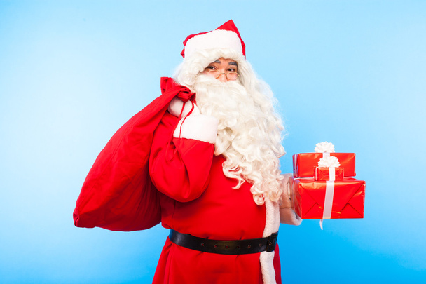 santa claus with gifts on hands on blue background - Фото, зображення