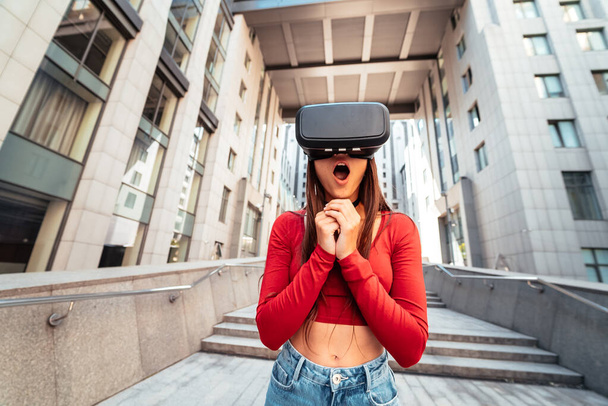 A woman in a virtual reality helmet walks down the street - Foto, afbeelding