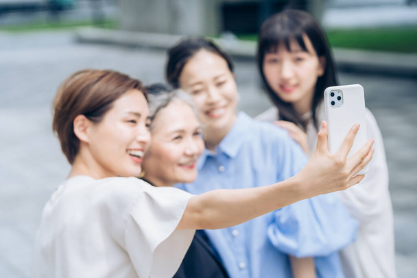 Women of various ages taking commemorative photos outdoors - Photo, Image