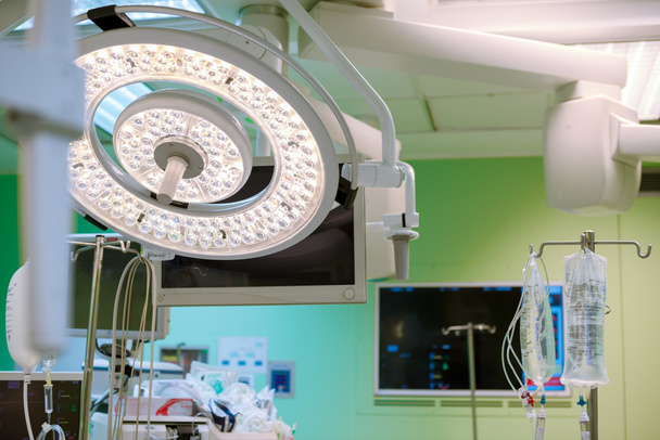 Lampy chirurgiczne w sali chirurgii operacji. Połowa jasność. Zielony oddanych światła jest na tle otwarte podczas zabiegu. Może być używany na swojej stronie internetowej, czasopisma, broszury lub reklama. - Zdjęcie, obraz