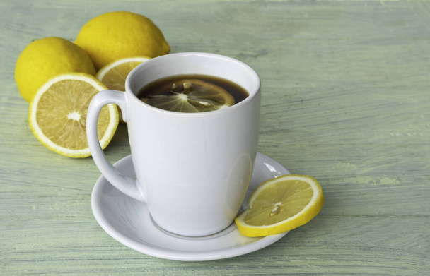 Black coffee, lemon slices, in white ceramic cup and yellow lemon on old wooden background. - Fotografie, Obrázek