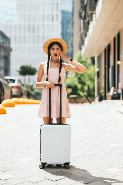 Young beautiful woman with a suitcase on the background of a modern city - Photo, Image