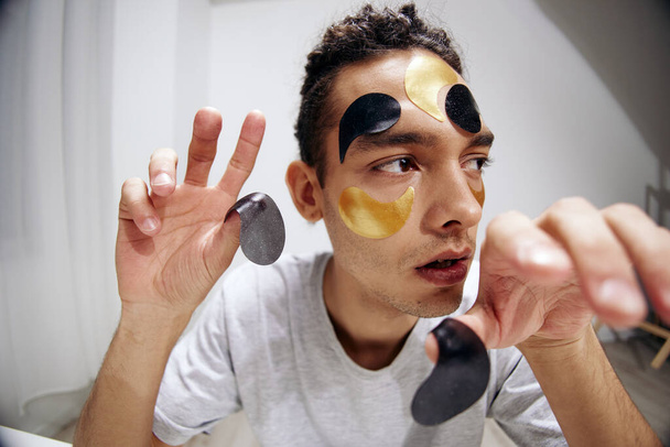 Молодой человек черно-золотые пятна на косметологии лица изолированный фон. Высокое качество фото - Фото, изображение
