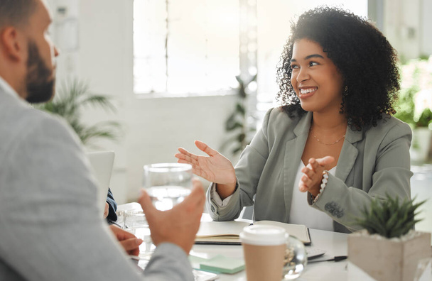 Businesspeople talking in a meeting together at work. Business professionals talking and planning in an office. Young mixed race businesswoman with a curly afro explaining an idea to colleagues at a - Foto, Imagen