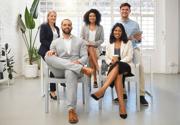Портрет группы из пяти веселых разнообразных бизнесменов, сидящих вместе за работой. Профессионалы бизнеса проводят встречу в офисе. Коллеги планируют вместе. - Фото, изображение