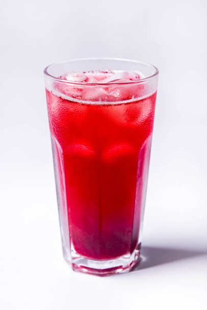 Homemade raspberry and apple compote in a transparent glass glass with ice. The glass stands on a white background, - Φωτογραφία, εικόνα