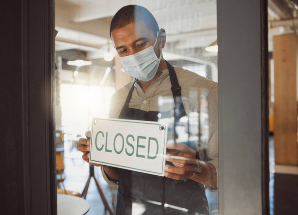 Business owner closing their shop in the pandemic. Boss hanging a closed sign in shop door in quarantine. Small business owner advertising that his restaurant is closed. Businessman wearing a mask. - Fotó, kép