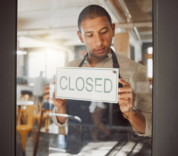 Businessman advertising that his shop is closed. Young business owner closing his restaurant. Shop owner hanging a closed sign in his store. Diner owner hanging a message in his shop entrance. - Foto, Imagem