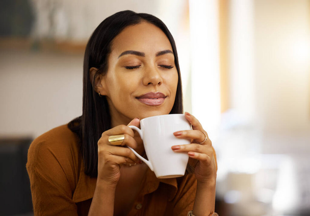 Młody szczęśliwy piękny mieszane rasy kobieta ciesząc się filiżankę kawy sam w domu. Latynoska kobieta po dwudziestce uśmiechnięta podczas picia filiżanki herbaty w domu. - Zdjęcie, obraz