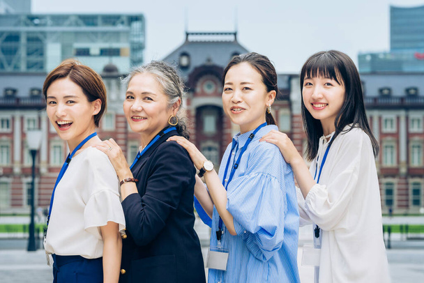 four business women lined up with smiles outdoors - 写真・画像