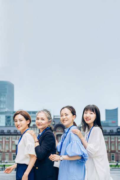 four business women lined up with smiles outdoors - 写真・画像