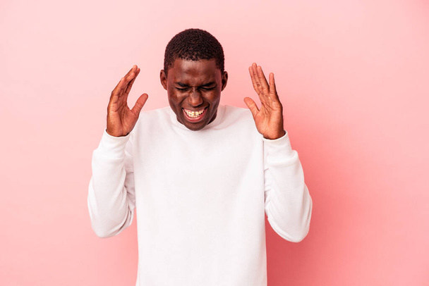 Молодий афроамериканець ізольований на рожевому фоні радісним сміхом. Концепція щастя. - Фото, зображення
