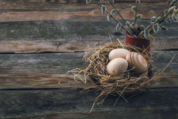 Easter decoration with wooden eggs in bascket and straw on wooden background - Foto, Imagem