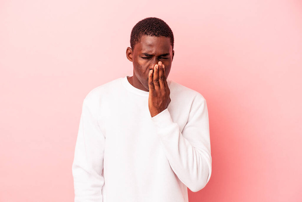 Νεαρός Αφροαμερικάνος απομονωμένος σε ροζ φόντο χασμουρείται δείχνοντας μια κουρασμένη χειρονομία που καλύπτει το στόμα με το χέρι. - Φωτογραφία, εικόνα