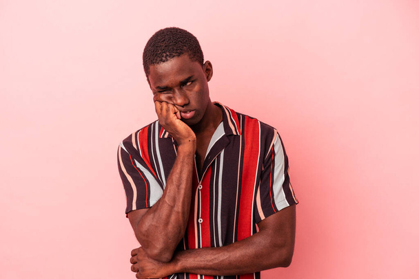 Fiatal afro-amerikai férfi elszigetelt rózsaszín háttér, aki úgy érzi, szomorú és töprengő, nézi a másolás tér. - Fotó, kép