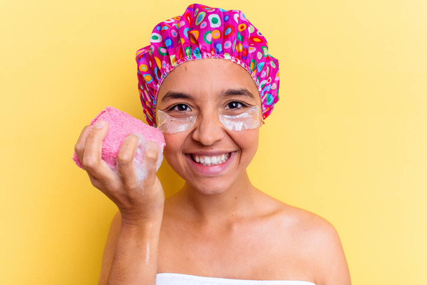 Молодая женщина смешанной расы принимает ванну, держа губку с повязками под глазом - Фото, изображение