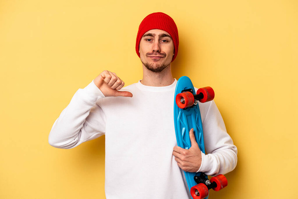 Young skater caucasian man isolated on yellow background feels proud and self confident, example to follow. - Zdjęcie, obraz