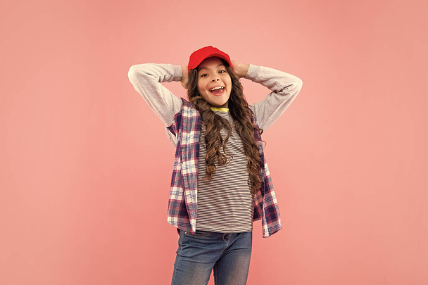 smiling child in checkered shirt and cap on pink background, fashionista. - Fotó, kép