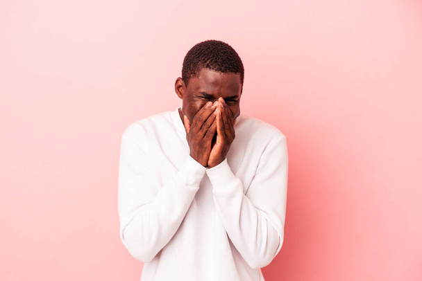 Giovane uomo afroamericano isolato su sfondo rosa ridendo di qualcosa, coprendo la bocca con le mani. - Foto, immagini