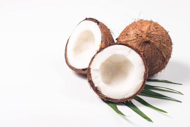 Ripe half cut coconut with green leaves on a white background. Isolated concept. - Photo, Image