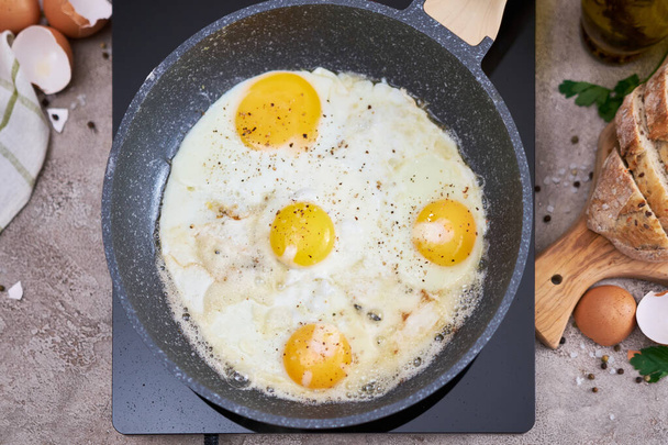 Fried Egg in cast iron frying pan on black induction hob. - Foto, Imagem