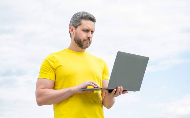 man working online on laptop on sky background. - Photo, Image