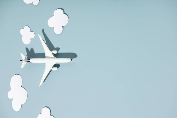 Miniature toy airplane and paper clouds on colorful background. Travel, vacations, tourism, airlines, low cost flights concept. Top view, flat lay. - Foto, imagen
