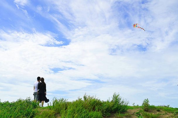 Чоловік і жінка спостерігають за веселковим змієм, що летить на блакитному небі
. - Фото, зображення