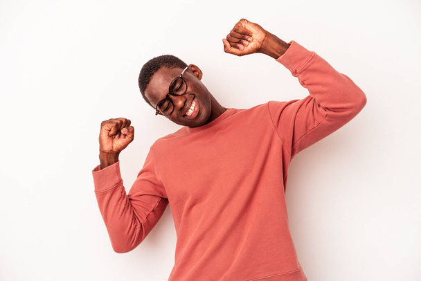 Junger afrikanisch-amerikanischer Mann, isoliert auf weißem Hintergrund, feiert einen besonderen Tag, springt und hebt energisch die Arme. - Foto, Bild