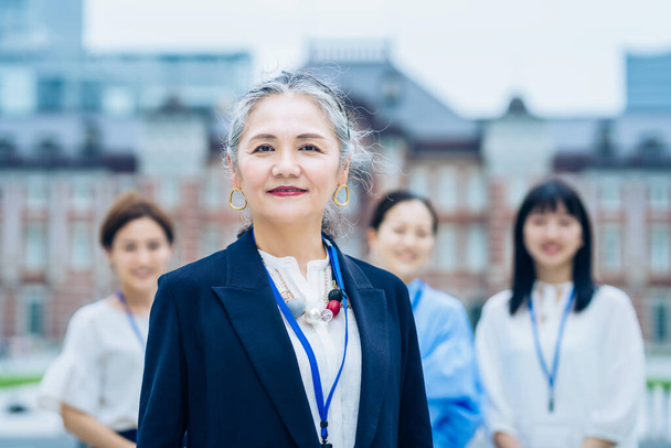 A business team centered on gray-haired woman outdoors - 写真・画像