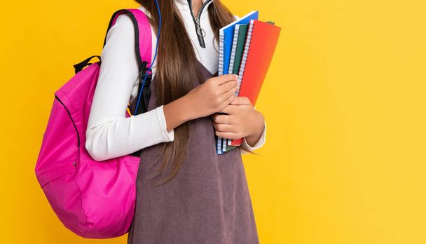 happy child in headphones with school backpack with workbook on yellow background. - Foto, imagen