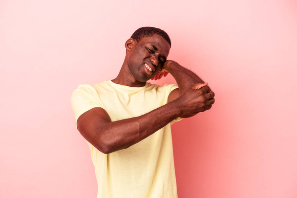 Young African American man isolated on pink background having a neck pain due to stress, massaging and touching it with hand. - 写真・画像