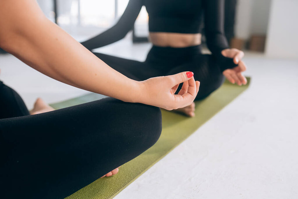 Two young women meditating in lotus pose. Yoga - Φωτογραφία, εικόνα