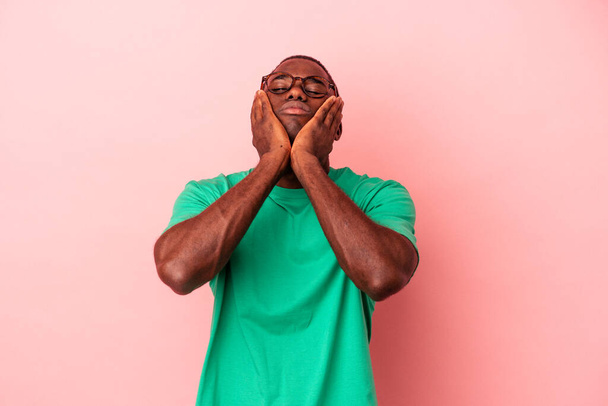 Jeune homme afro-américain isolé sur fond rose pleurant et pleurant de façon disconsolante. - Photo, image