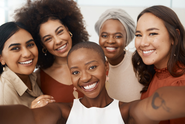 Happy diverse group of young female friends taking a selfie together. Team of cheerful and joyful businesswomen taking a photo in an office at work. - Foto, Imagem