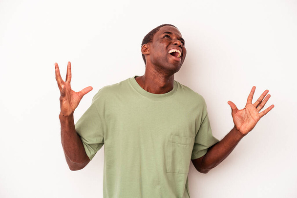 Junger afrikanisch-amerikanischer Mann isoliert auf weißem Hintergrund schreit in den Himmel, blickt frustriert auf. - Foto, Bild