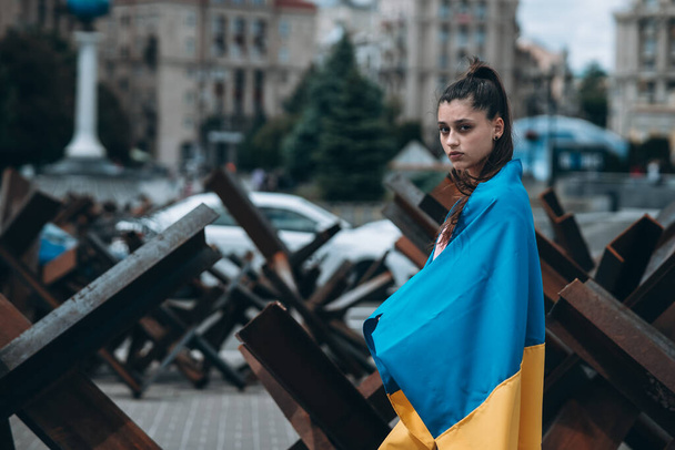 Молодая женщина с национальным флагом Украины гуляет по городу - Фото, изображение