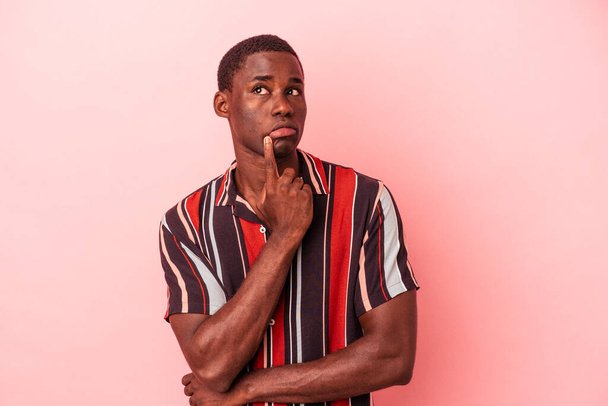Young African American man isolated on pink background looking sideways with doubtful and skeptical expression. - Foto, Imagen