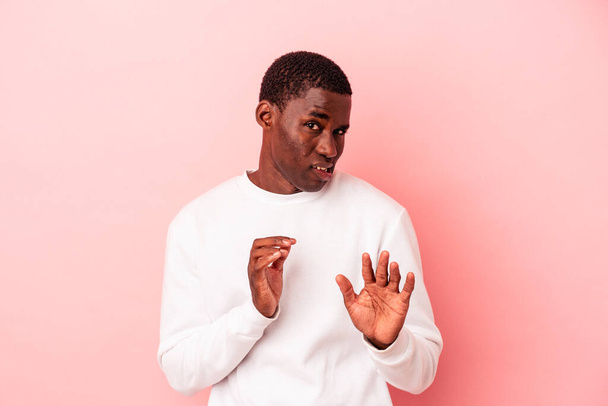 Молодой африканский американец, изолированный на розовом фоне, отвергает кого-то, демонстрирующего отвращение. - Фото, изображение