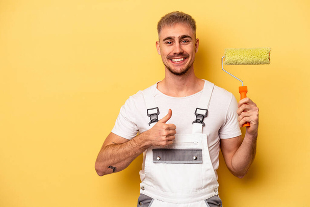 Young painter man isolated on yellow background smiling and raising thumb up - Foto, Imagem