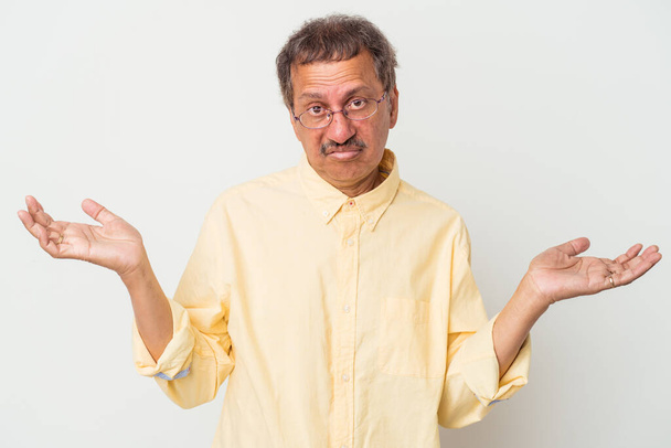 Middle aged indian man isolated on white background doubting and shrugging shoulders in questioning gesture. - Foto, Imagem