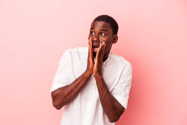 Νεαρός Αφροαμερικάνος απομονωμένος σε ροζ φόντο φοβισμένος και φοβισμένος. - Φωτογραφία, εικόνα
