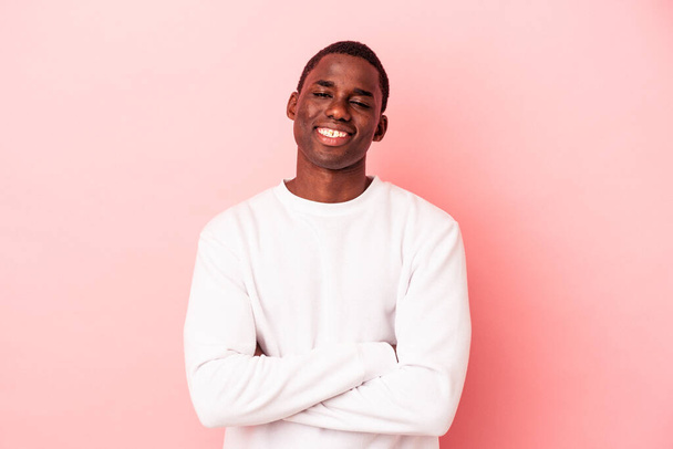 Fiatal afro-amerikai férfi elszigetelt rózsaszín háttér, aki úgy érzi, magabiztos, keresztbe karok eltökélten. - Fotó, kép