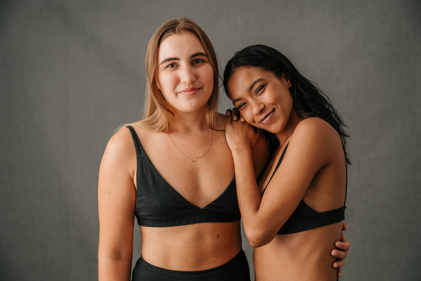 Two relaxed and content smiling girlfriends posing in the studio before workout. High quality photo - Photo, image