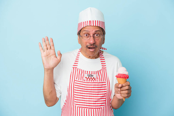 Senior american ice cream man holding an ice cream isolated on blue background surprised and shocked. - Fotó, kép
