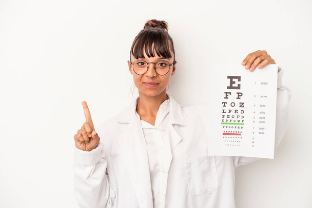 jong gemengd ras opticien vrouw doen een test geïsoleerd op witte achtergrond tonen nummer een met vinger. - Foto, afbeelding
