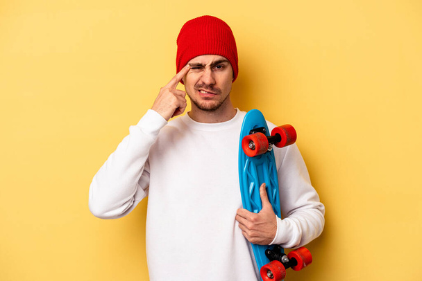 Young skater caucasian man isolated on yellow background showing a disappointment gesture with forefinger. - Photo, image