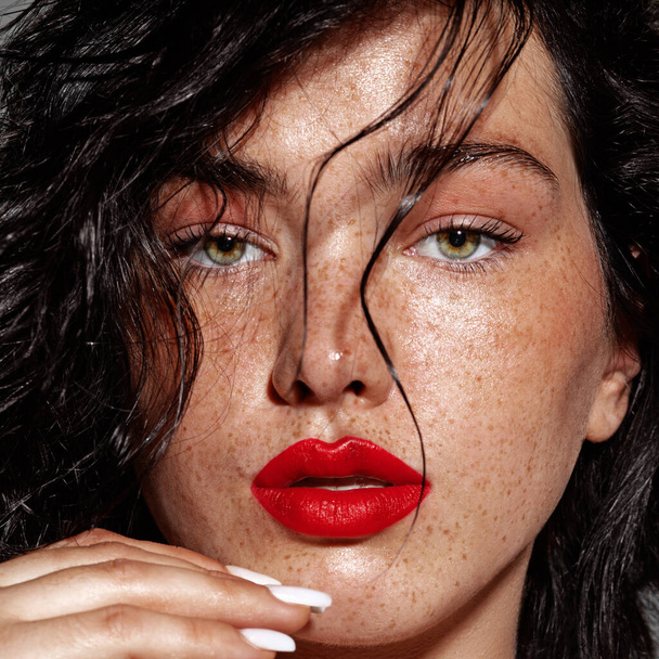 beauty young woman face with a lot of freckles and red lips, hand near face, close up - Foto, Imagem