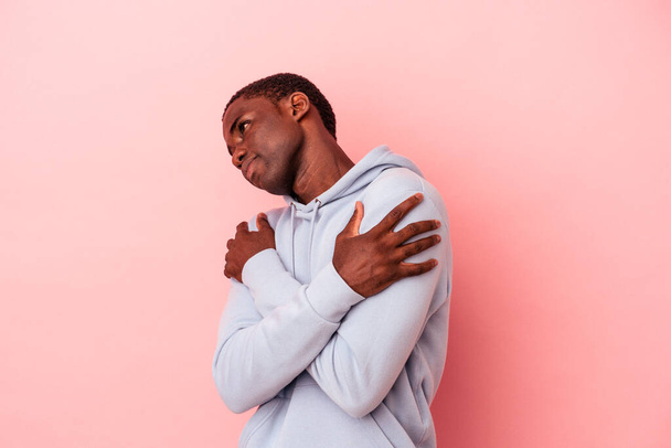 Молодий афроамериканець ізольований на рожевих задніх обіймах, усміхаючись безтурботно і щасливий. - Фото, зображення