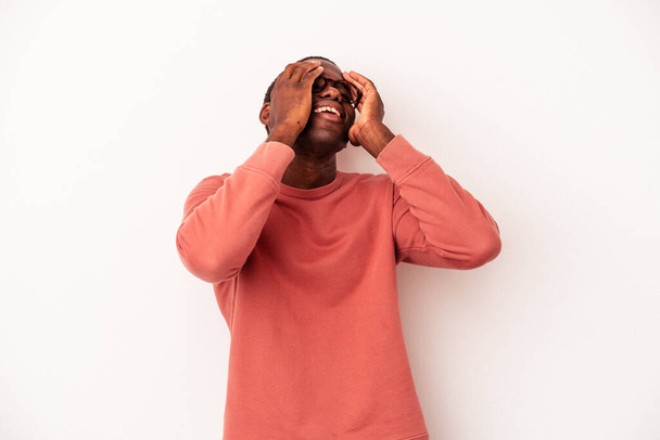 A fiatal afro-amerikai férfi fehér háttérrel elszigetelve nevetve tartja a kezét a fején. Boldogság fogalma. - Fotó, kép